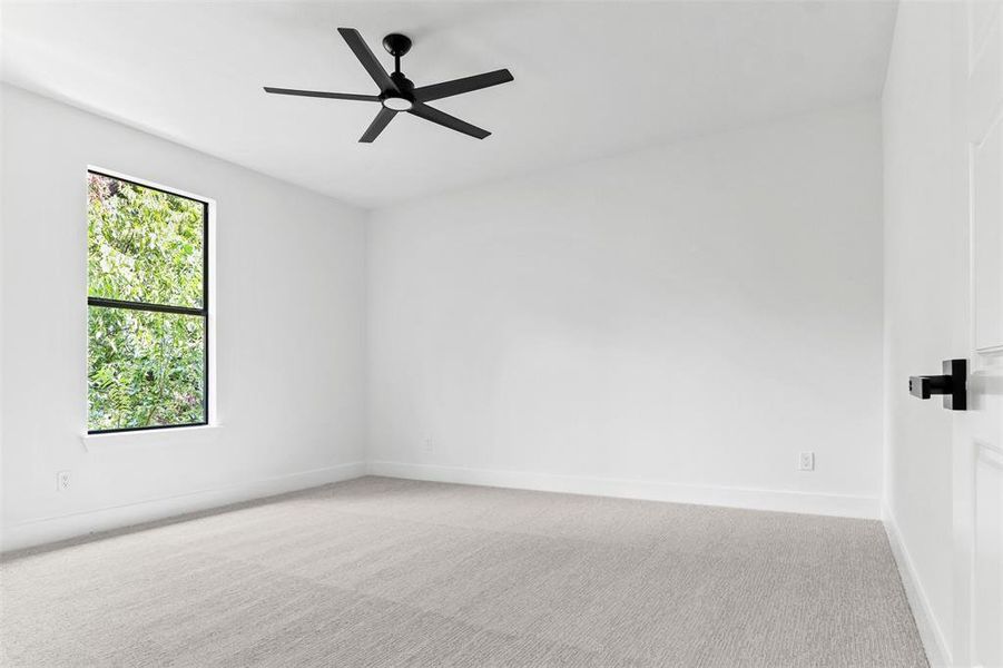 Empty room with light colored carpet and ceiling fan