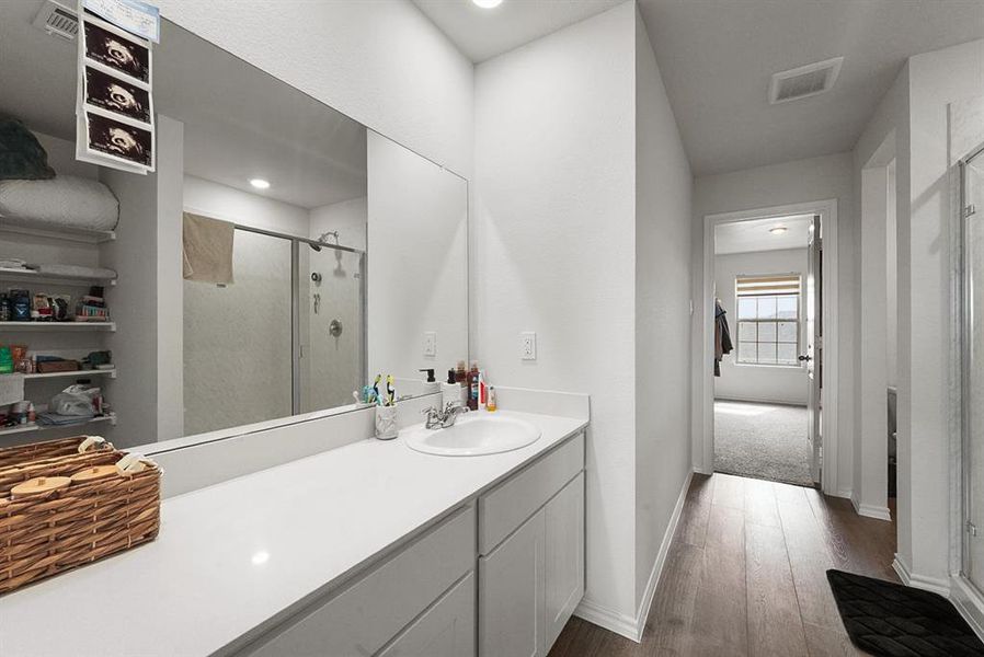 Bathroom featuring a single vanity with an integrated sink, polished countertop, and ample storage cabinetry