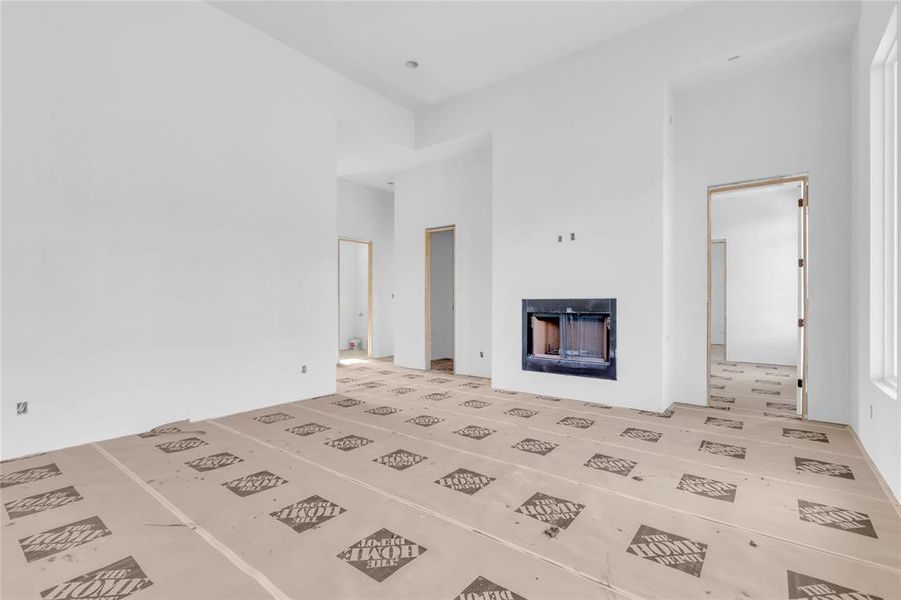Unfurnished living room featuring a fireplace and a high ceiling Unfurnished living room featuring a fireplace and a high ceiling