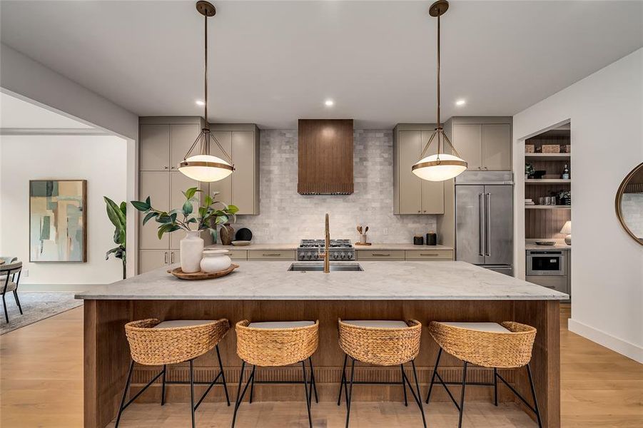 Kitchen featuring a breakfast bar, light wood finished floors, decorative backsplash, a center island with sink, and recessed lighting Kitchen featuring a breakfast bar, light wood finished floors, decorative backsplash, a center island with sink, and recessed lighting
