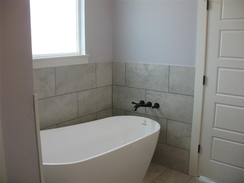 Bathroom with a soaking tub, tile walls, and tile patterned floors