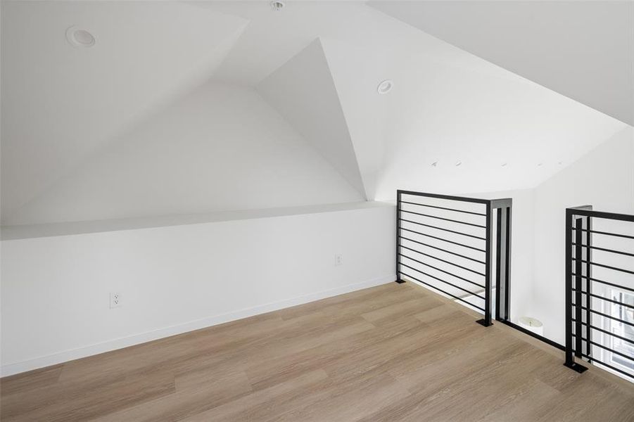 Bonus room featuring lofted ceiling, baseboards, and wood finished floors