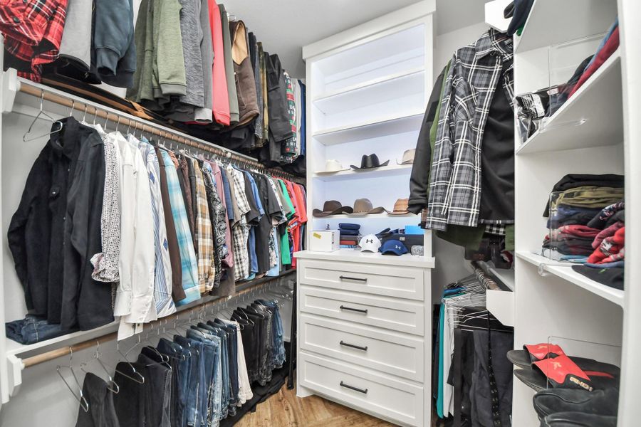 Spacious walk-in closet featuring ample hanging space, open shelving, and built-in drawers for organized storage.