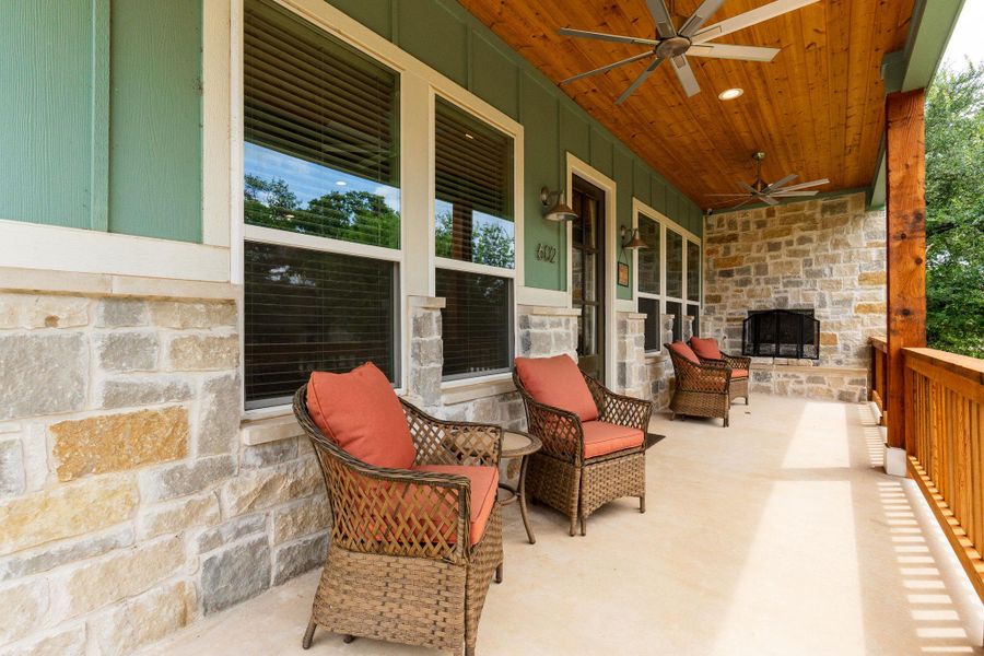 A spacious covered porch features a fireplace and wood-paneled ceiling, offering a relaxing outdoor retreat.