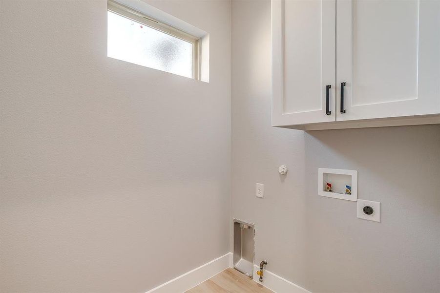 Washroom featuring gas dryer hookup, cabinet space, washer hookup, light wood-style flooring, and hookup for an electric dryer