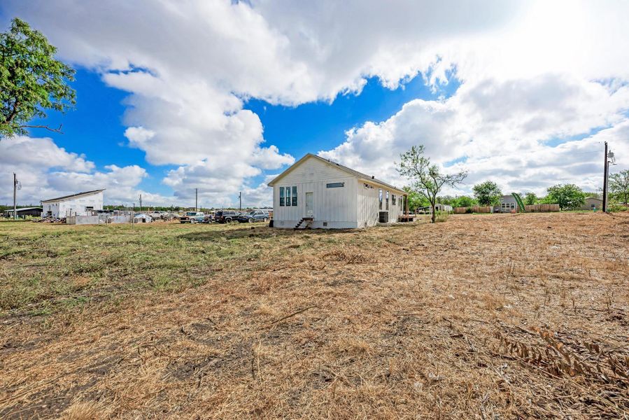 An expansive open lot surrounds a classic siding-clad structure under wide open skies.