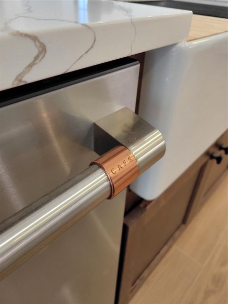 This photo showcases a modern kitchen detail with a sleek, stainless steel CAFE appliance handle and a stylish copper accent. This photo showcases a modern kitchen detail with a sleek, stainless steel CAFE appliance handle and a stylish copper accent.