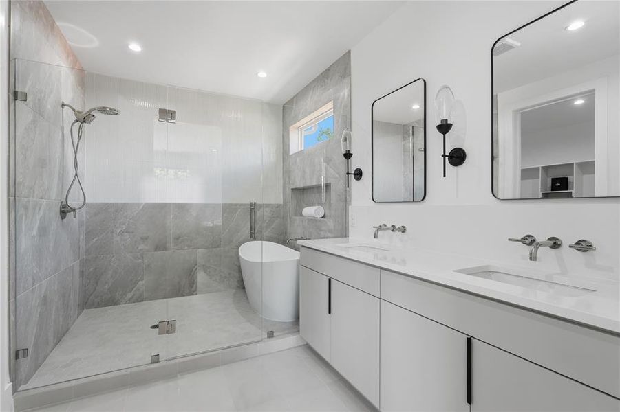 Spacious bathroom featuring a glass-enclosed shower, freestanding bathtub, dual vanity with undermount sinks, wall-mounted faucets, and contemporary mirrors with sconce lighting