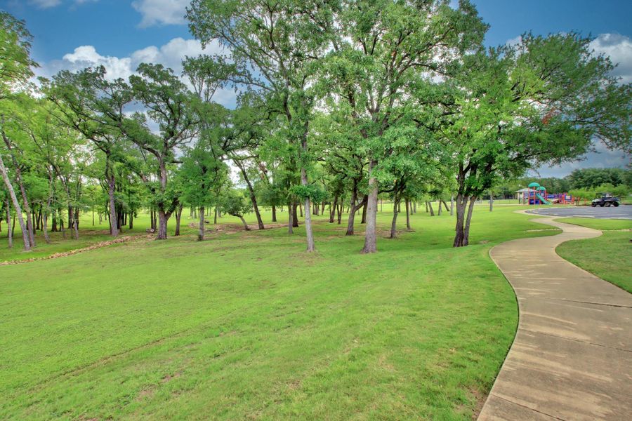 The property features a well-maintained lawn and numerous mature trees, providing a natural setting