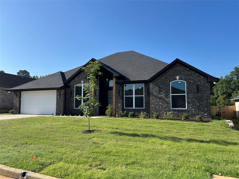 Ranch-style home featuring brick siding, a garage, driveway, and roof with shingles