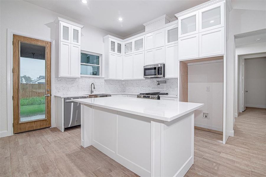 Kitchen featuring appliances with stainless steel finishes, tasteful backsplash, light wood-style flooring, white cabinets, and recessed lighting Kitchen featuring appliances with stainless steel finishes, tasteful backsplash, light wood-style flooring, white cabinets, and recessed lighting