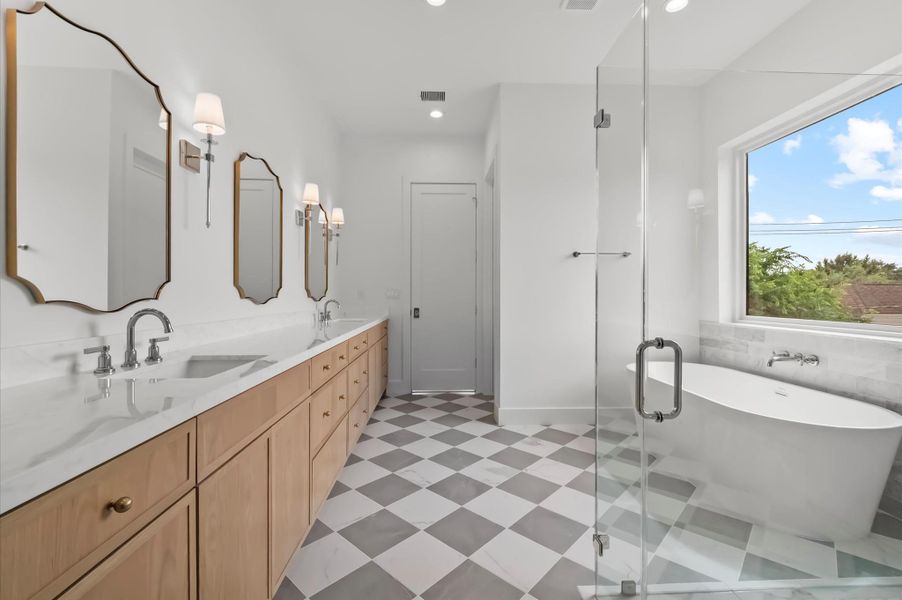 Luxurious primary bathroom featuring dual vanities, a soaking tub, and a separate walk-in shower. Luxurious primary bathroom featuring dual vanities, a soaking tub, and a separate walk-in shower.