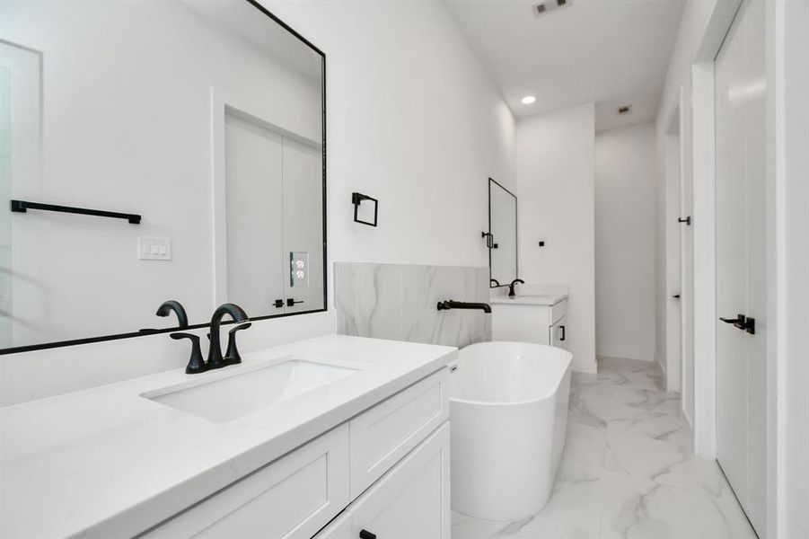 Another view of the luxury that is the primary bath, highlighted the two beautifully appointed vanity areas, spacious soaking tub and walk in closet