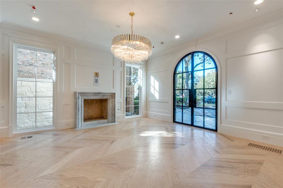 Unfurnished living room featuring an inviting chandelier, crown molding, and light parquet flooring