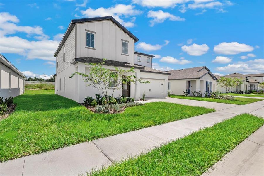 Front exterior of a new home in Peach Crossings, Winter Haven, FL, highlighting curb appeal (Image 18).