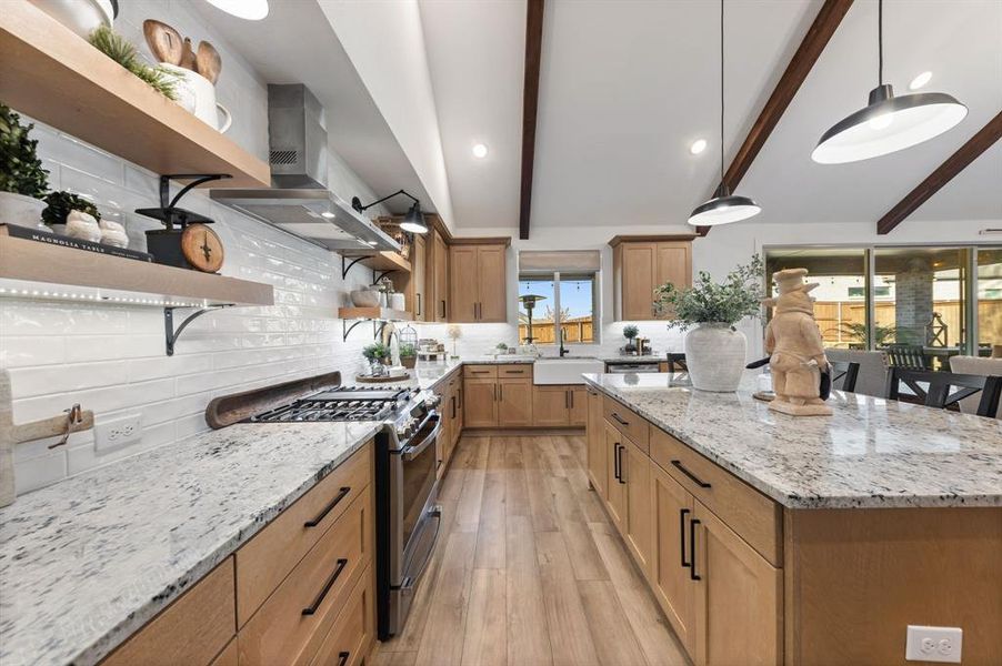 Kitchen with gas cooktop, double ovens, stainless appliances, large island, and abundant storage.