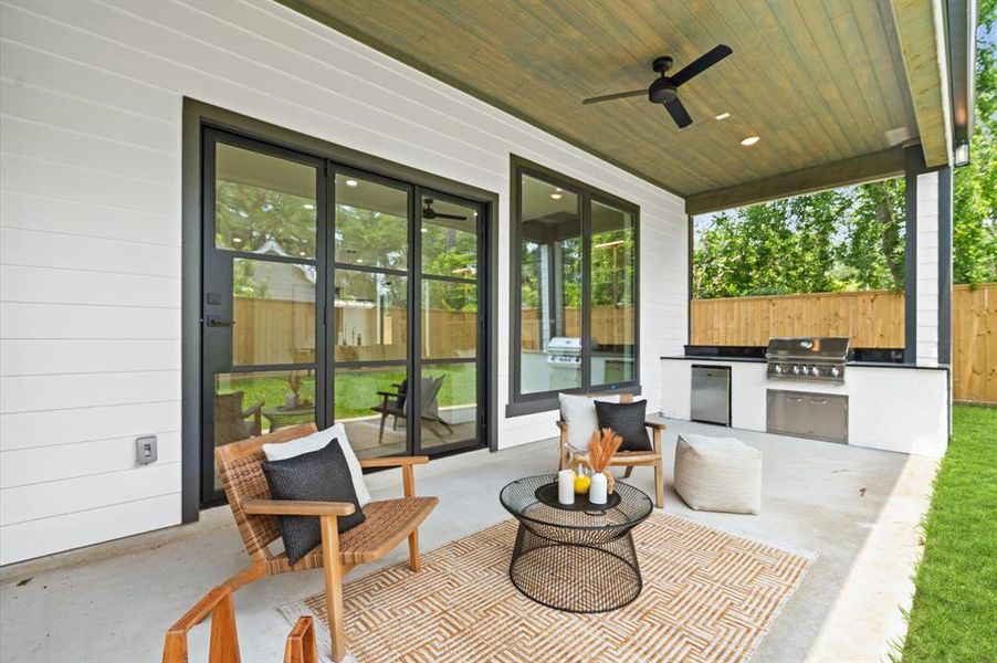 Large covered outdoor patio with built-in gas grill and beverage cooler.