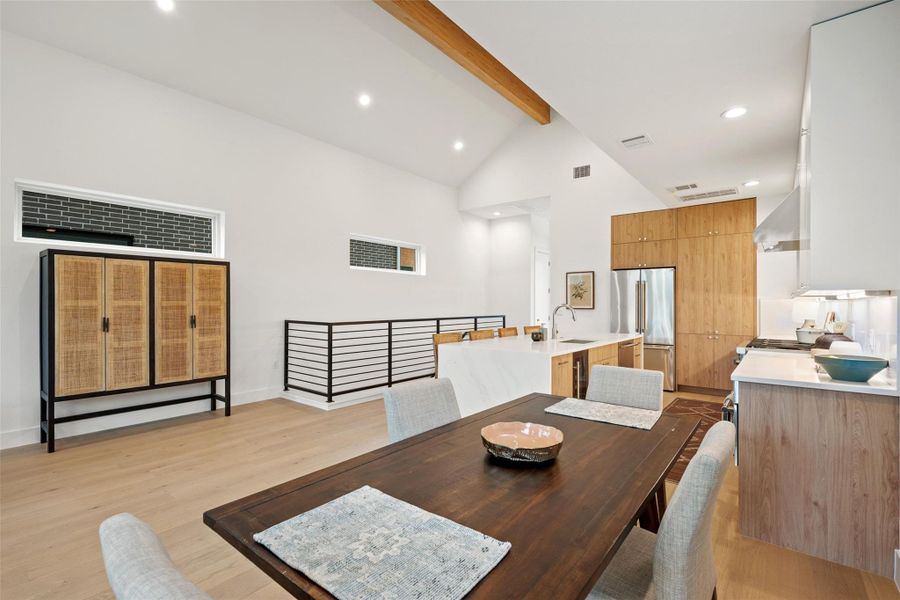 A vibrant open-concept dining area flows seamlessly into a contemporary kitchen, illuminated by recessed lighting and a vaulted ceiling. A vibrant open-concept dining area flows seamlessly into a contemporary kitchen, illuminated by recessed lighting and a vaulted ceiling.