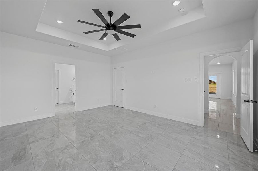 Tiled spare room with a tray ceiling and ceiling fan