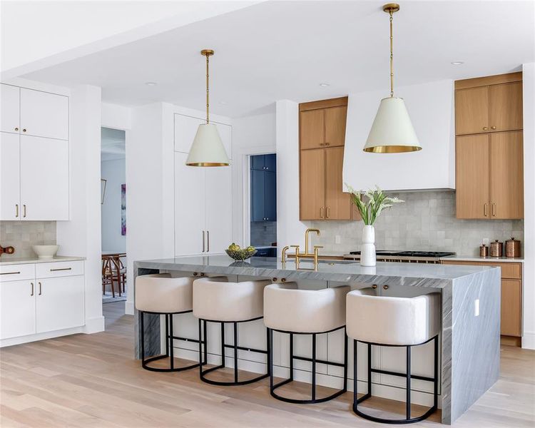 Kitchen with white cabinetry, tasteful backsplash, decorative light fixtures, and light wood-type flooring