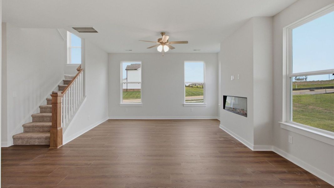 Open gathering room with fireplace and staircase to second floor