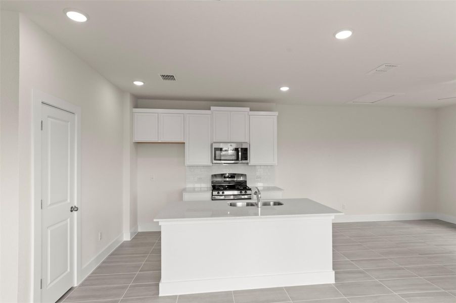 Kitchen with decorative backsplash, baseboards, white cabinetry, a sink, and stainless steel appliances