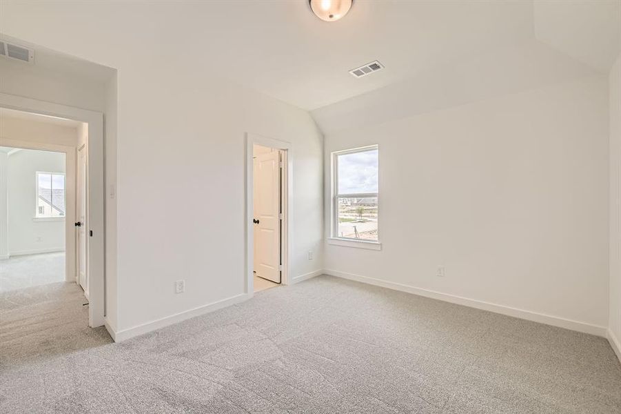 Unfurnished bedroom featuring light colored carpet, baseboards, and lofted ceiling Unfurnished bedroom featuring light colored carpet, baseboards, and lofted ceiling