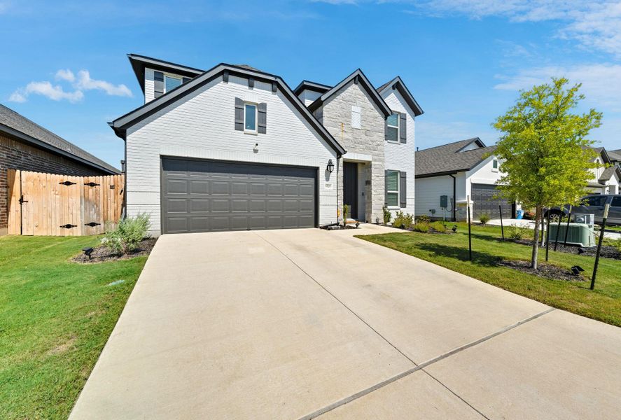 Traditional-style house with concrete driveway, a garage, and stone siding Traditional-style house with concrete driveway, a garage, and stone siding