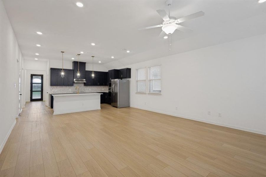 Open-concept living area featuring light wood-finish flooring, recessed lighting, and a contemporary ceiling fan