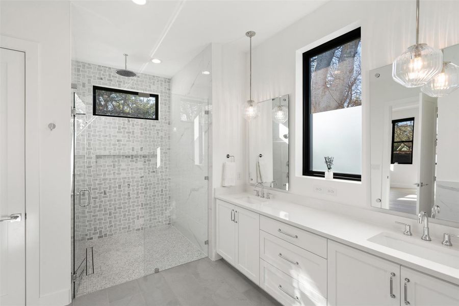 Curbless walk-in shower designed with with quartz slabs and marble tile work. Rain shower feature in addition to the other shower head