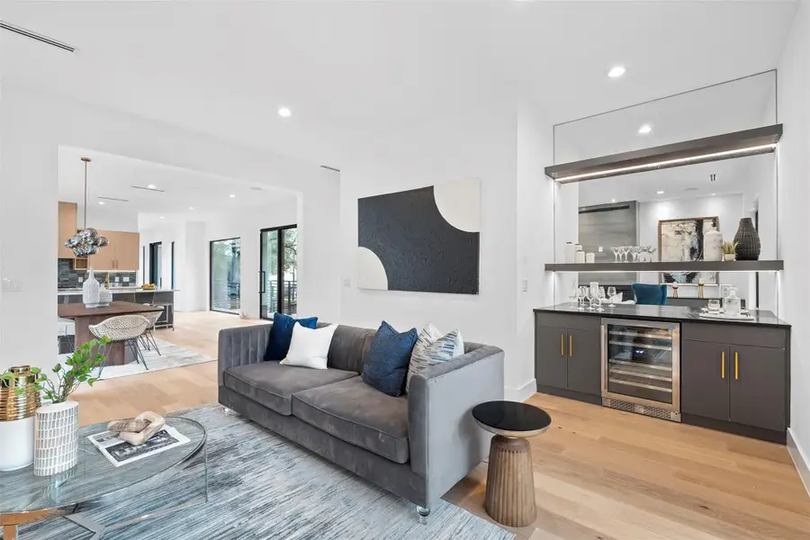 Living area featuring light wood flooring, a built-in bar with a wine refrigerator, and recessed lighting