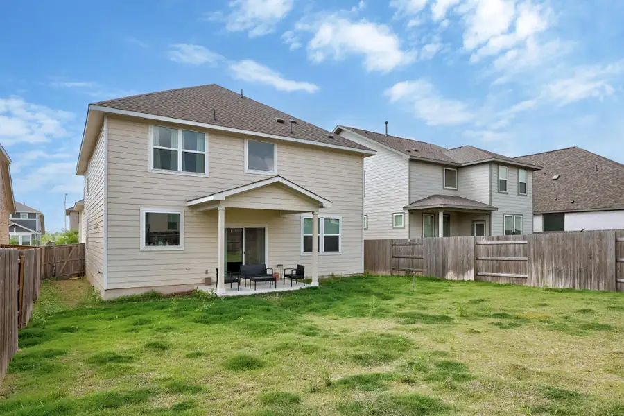 Expansive backyard featuring a covered patio, sliding glass door access, and a wood privacy fence