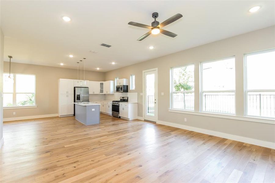 Kitchen with white cabinetry, decorative light fixtures, a center island, light wood-type flooring, and appliances with stainless steel finishes