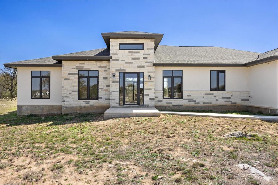 View of front of home featuring stucco siding, stone siding, and a shingled roof