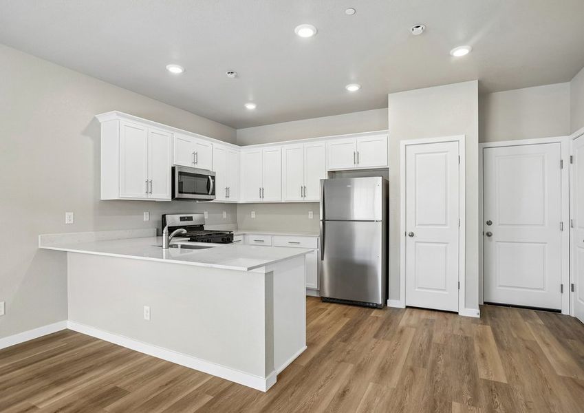 The kitchen has stainless steel appliances and plank flooring.