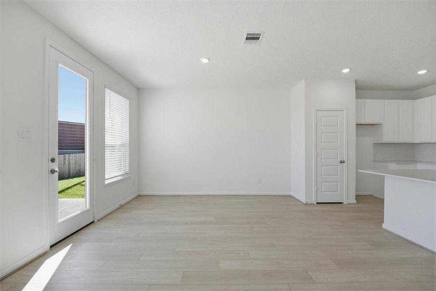 Create lasting memories around the table with family and friends in this inviting dining room! It showcases high ceilings, large windows with privacy blinds, access door to the back patio and yard, vinyl plank flooring, and recessed lighting for a warm and welcoming atmosphere.