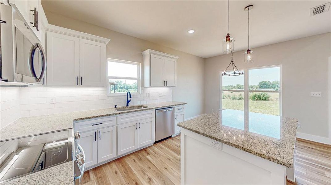 Kitchen featuring appliances with stainless steel finishes, light wood-type flooring, a kitchen island, white cabinets, and recessed lighting Kitchen featuring appliances with stainless steel finishes, light wood-type flooring, a kitchen island, white cabinets, and recessed lighting