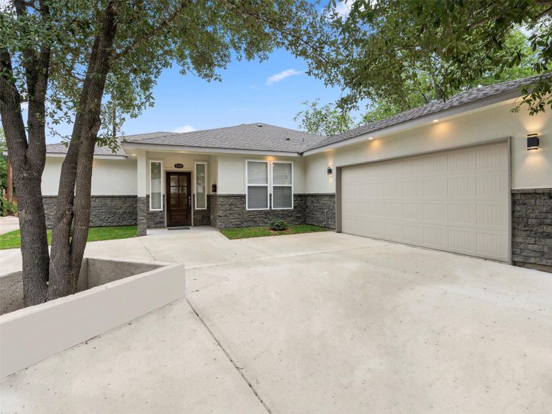 View of front of house with stucco siding, stone siding, driveway, and a garage View of front of house with stucco siding, stone siding, driveway, and a garage