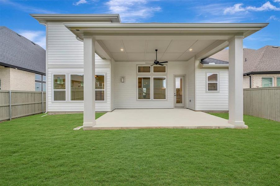 The property features a covered patio with an outdoor ceiling fan and recessed lighting, overlooking a well-maintained lawn