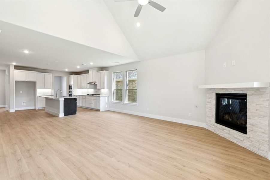 Unfurnished living room featuring high vaulted ceiling, light wood-style flooring, recessed lighting, a fireplace, and a ceiling fan Unfurnished living room featuring high vaulted ceiling, light wood-style flooring, recessed lighting, a fireplace, and a ceiling fan