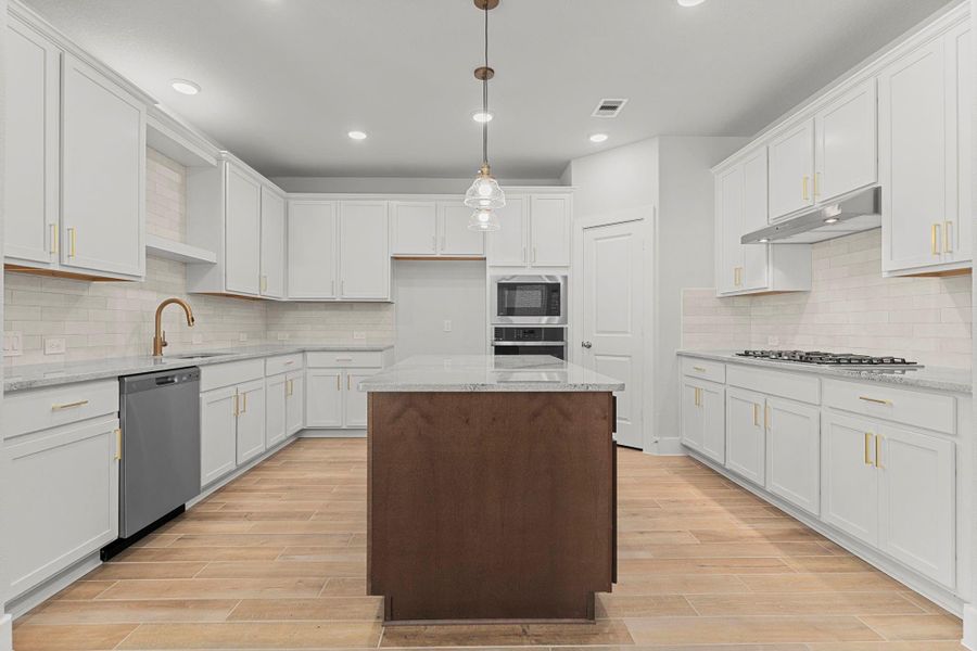 The gourmet kitchen is a chef’s dream—complete with pristine white shaker cabinets, a tile backsplash, granite countertops, stainless steel appliances, and a gorgeous pendant-lit island at its center. The gourmet kitchen is a chef’s dream—complete with pristine white shaker cabinets, a tile backsplash, granite countertops, stainless steel appliances, and a gorgeous pendant-lit island at its center.