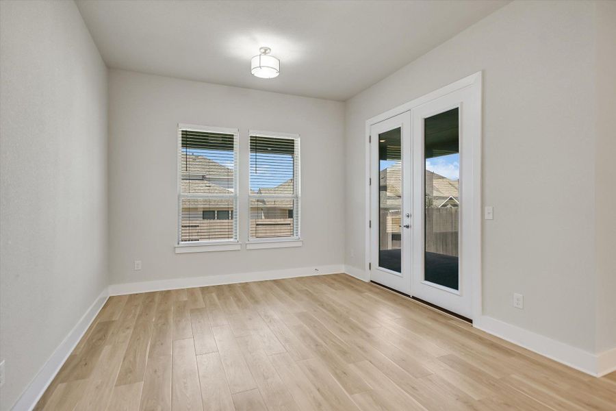 French doors open to the outdoors from this versatile space with light-toned wood-style flooring. French doors open to the outdoors from this versatile space with light-toned wood-style flooring.