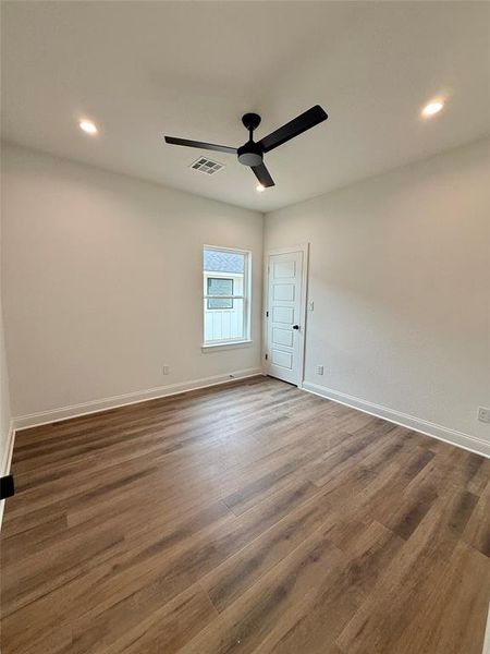 Spacious room featuring wood-finish flooring, a modern black ceiling fan, recessed lighting, and a multi-pane window