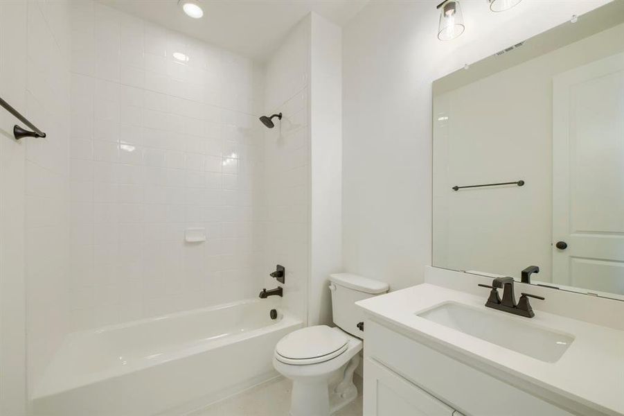 Bathroom featuring a white subway tile tub surround with matte black fixtures, a white vanity with a rectangular sink and matte black faucet, and a large wall-mounted mirror Bathroom featuring a white subway tile tub surround with matte black fixtures, a white vanity with a rectangular sink and matte black faucet, and a large wall-mounted mirror