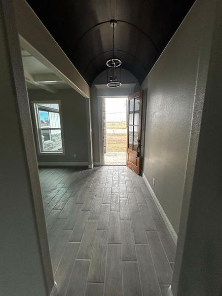 Hall featuring lofted ceiling, wood finished floors, and baseboards