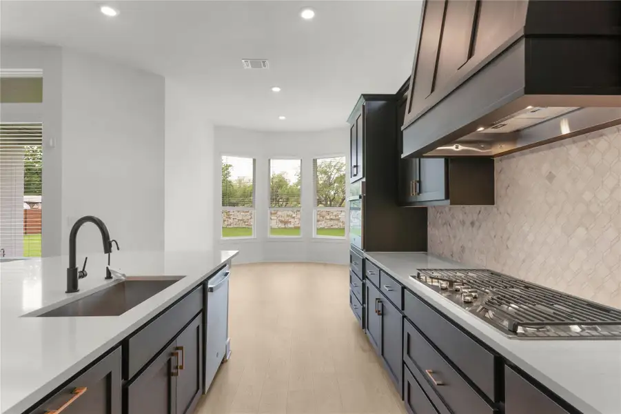 Kitchen with premium range hood, decorative backsplash, light countertops, and recessed lighting Kitchen with premium range hood, decorative backsplash, light countertops, and recessed lighting