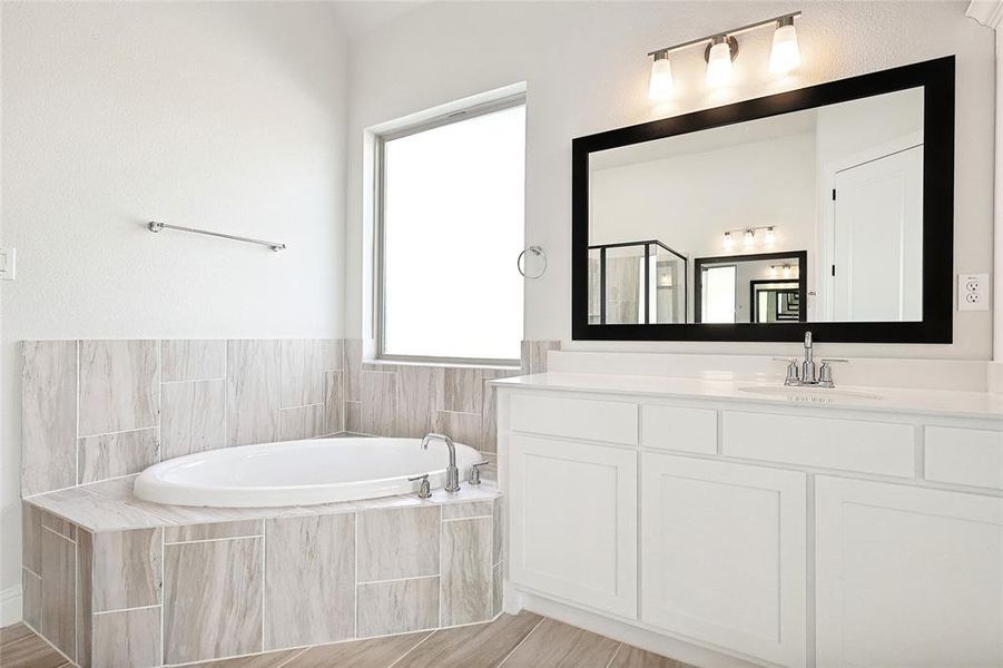 Bathroom with vanity, a relaxing tiled tub, and wood-type flooring