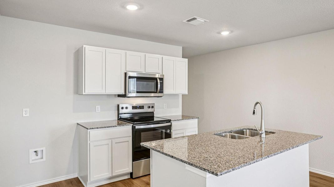 Kitchen featuring white cabinetry, stainless steel appliances, granite countertops, and wood-finish flooring Kitchen featuring white cabinetry, stainless steel appliances, granite countertops, and wood-finish flooring