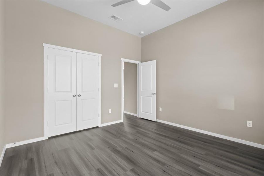 Unfurnished bedroom with dark wood-type flooring, a closet, and ceiling fan