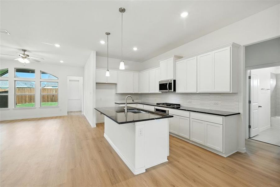 Kitchen with a kitchen island with sink, white cabinetry, stainless steel appliances, and light wood finished floors